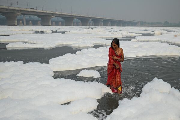 Верующая окунается в реку Джамна в преддверии праздника Чхатх в Нью-Дели 