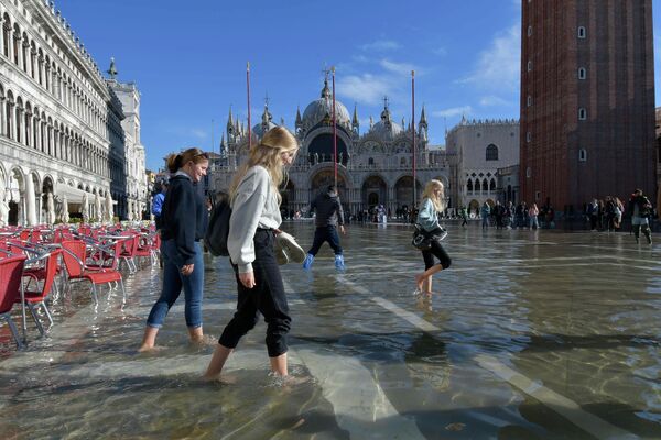 Люди гуляют по затопленной площади Сан-Марко в Венеции