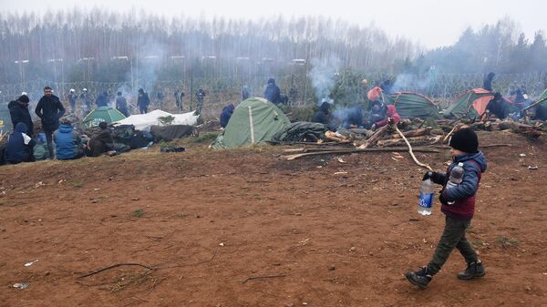 Мальчик несет бутылки с питьевой водой в лагере нелегальных мигрантов на белорусско-польской границе