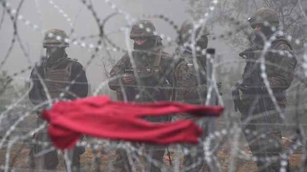 Польские военнослужащие возле заграждения из колючей проволоки у лагеря нелегальных мигрантов на белорусско-польской границе