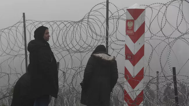 Беженцы возле заграждения из колючей проволоки в лагере нелегальных мигрантов на белорусско-польской границе