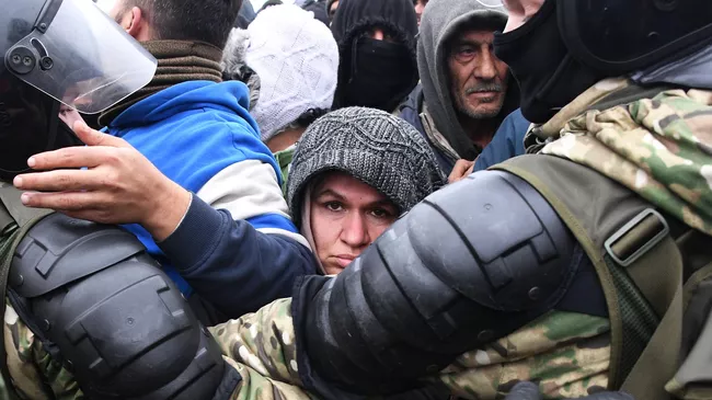Беженцы под контролем белорусских военнослужащих во время получения гуманитарной помощи в лагере нелегальных мигрантов на белорусско-польской границе