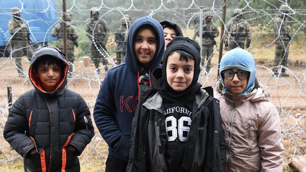 Дети возле заграждения из колючей проволоки в лагере нелегальных мигрантов на белорусско-польской границе