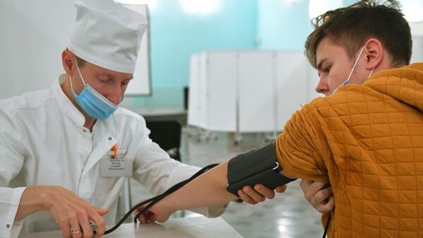 Врач измеряет артериальное давление пациенту пред вакцинацией препаратом Спутник Лайт 