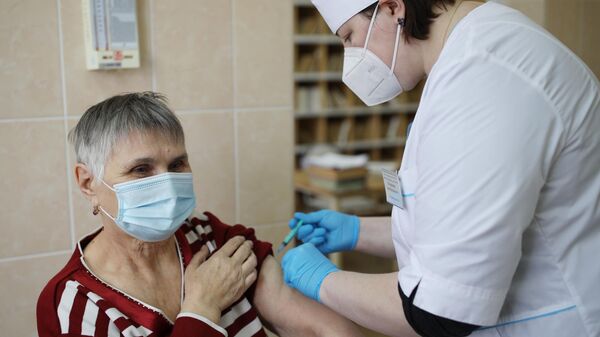 Медицинский сотрудник делает женщине прививку от коронавирусной инфекции
