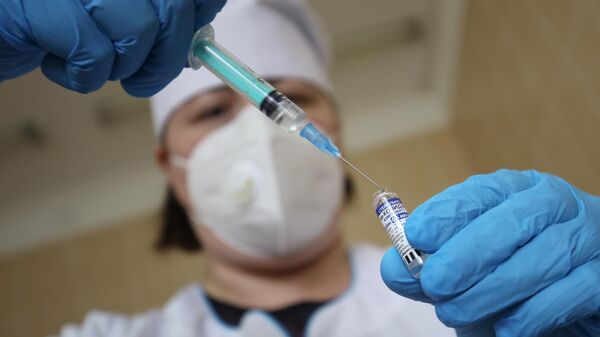 Медицинский сотрудник набирает в шприц препарат от коронавирусной инфекции Гам-Ковид-Вак