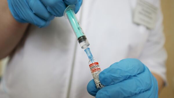 Медицинский сотрудник набирает в шприц препарат от коронавирусной инфекции