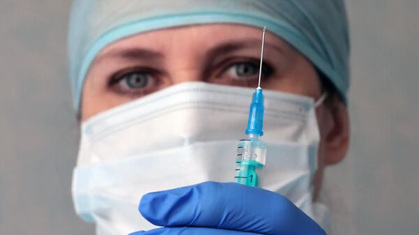 Медицинский работник держит в руках ампулу с российской вакциной против коронавирусной инфекции