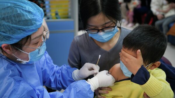 Медицинский работник вакцинирует ребенка в Китае
