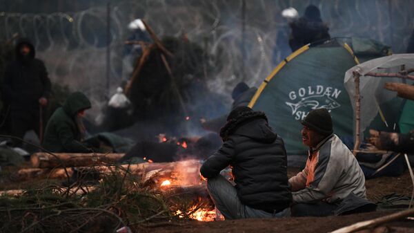 Люди греются у костра в лагере нелегальных мигрантов на белорусско-польской границе