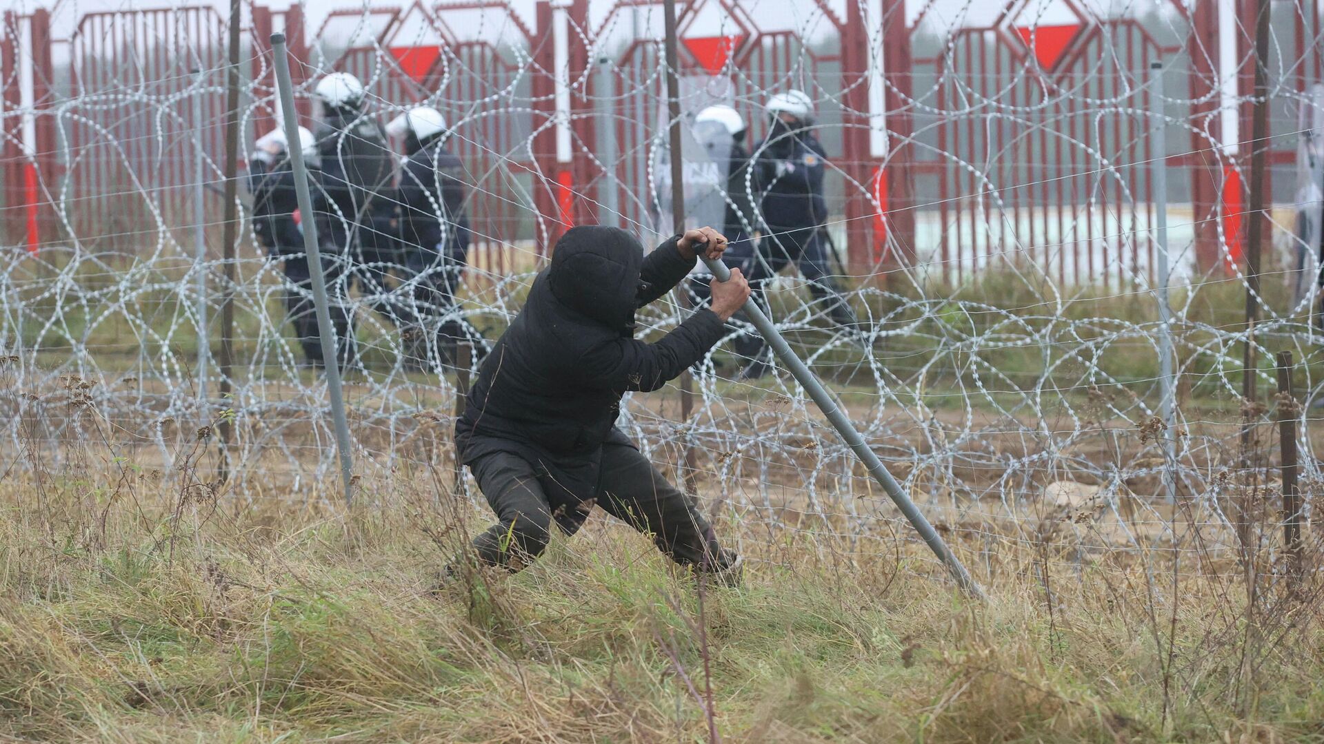 Мужчина ломает забор на белорусско-польской границе в районе КПП Брузги - Кузница  - РИА Новости, 1920, 16.11.2021