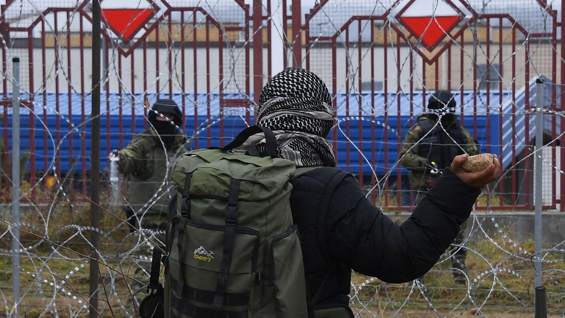 Мужчина бросает камень через проволочные заграждения на польско-белорусской границе в районе погранперехода Брузги - Кузница - РИА Новости, 1920, 16.11.2021