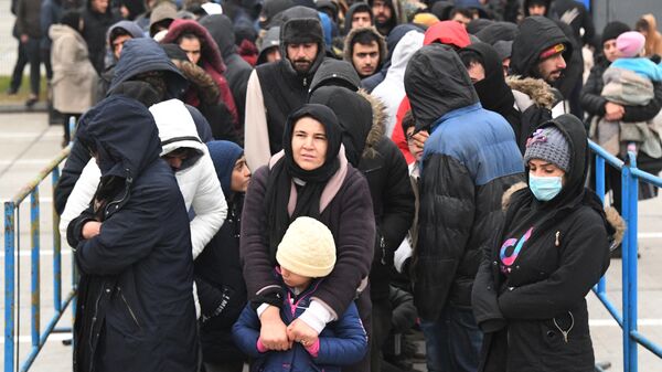 Беженцы с Ближнего Востока стоят в очереди за питанием в центре временного содержания мигрантов, оборудованном в логистическом центре в пункте пропуска Брузги