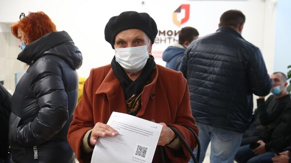 Женщина держит в руках распечатанный бумажный QR-код в многофункциональном центре госуслуг Мои документы в Волгограде