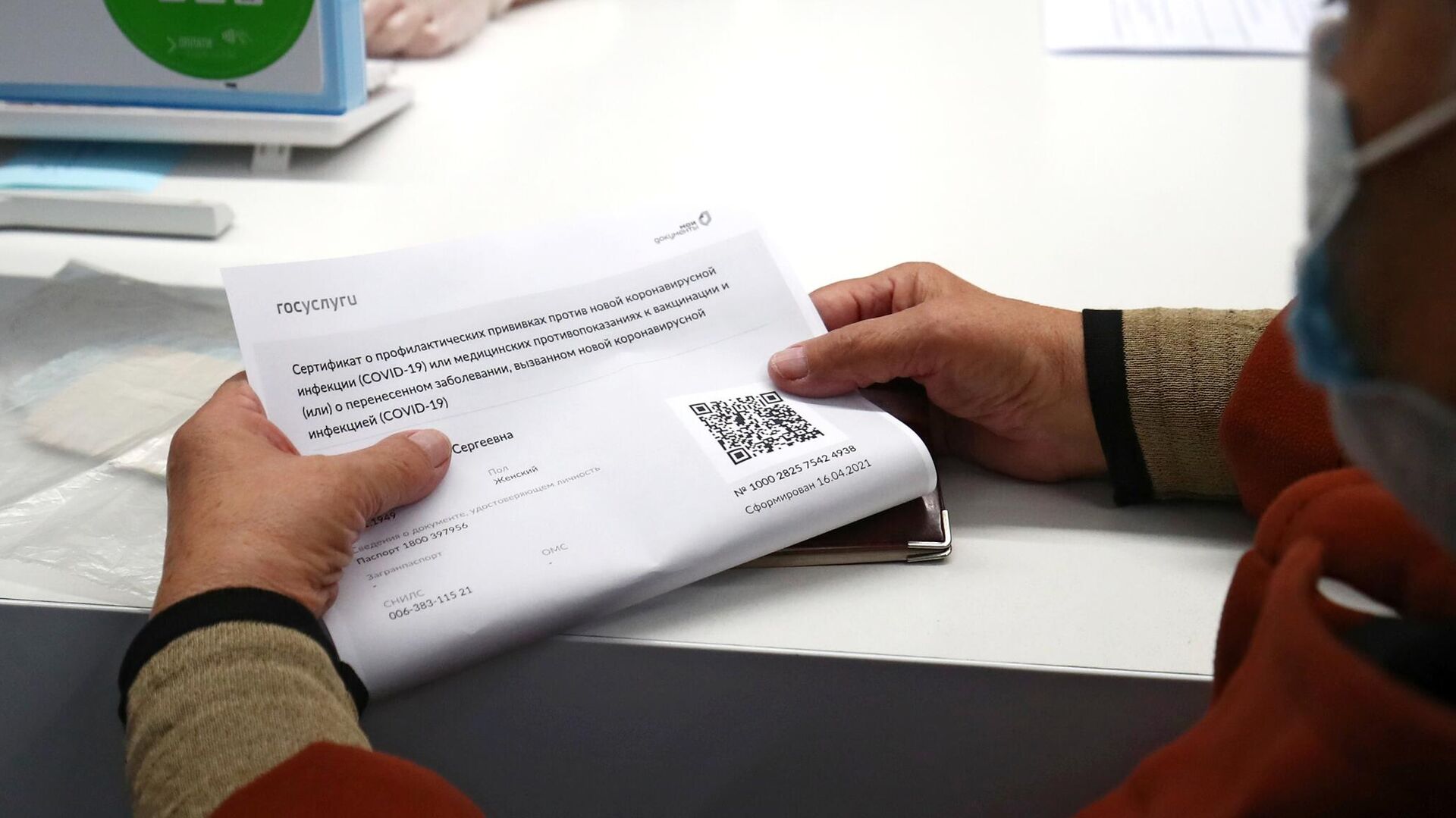 Женщина держит в руках распечатанный бумажный QR-код в многофункциональном центре госуслуг Мои документы в Волгограде - РИА Новости, 1920, 23.11.2021