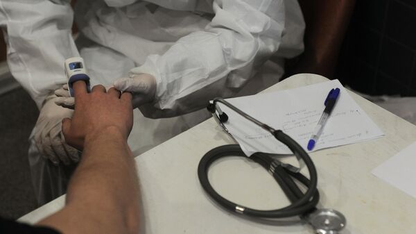Врач - терапевт проводит измерение уровня кислорода в крови пациенту на дому во время работы на выезде