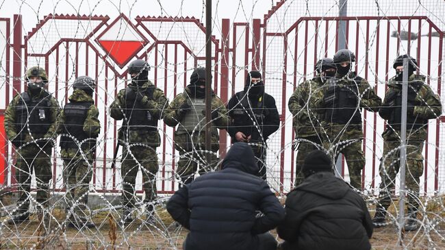 Беженцы с Ближнего Востока и польские военные у лагеря нелегальных мигрантов на белорусско-польской границе