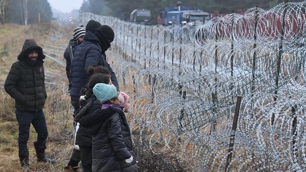 Люди из лагеря нелегальных мигрантов возле ограждений у лагеря нелегальных мигрантов на белорусско-польской границе