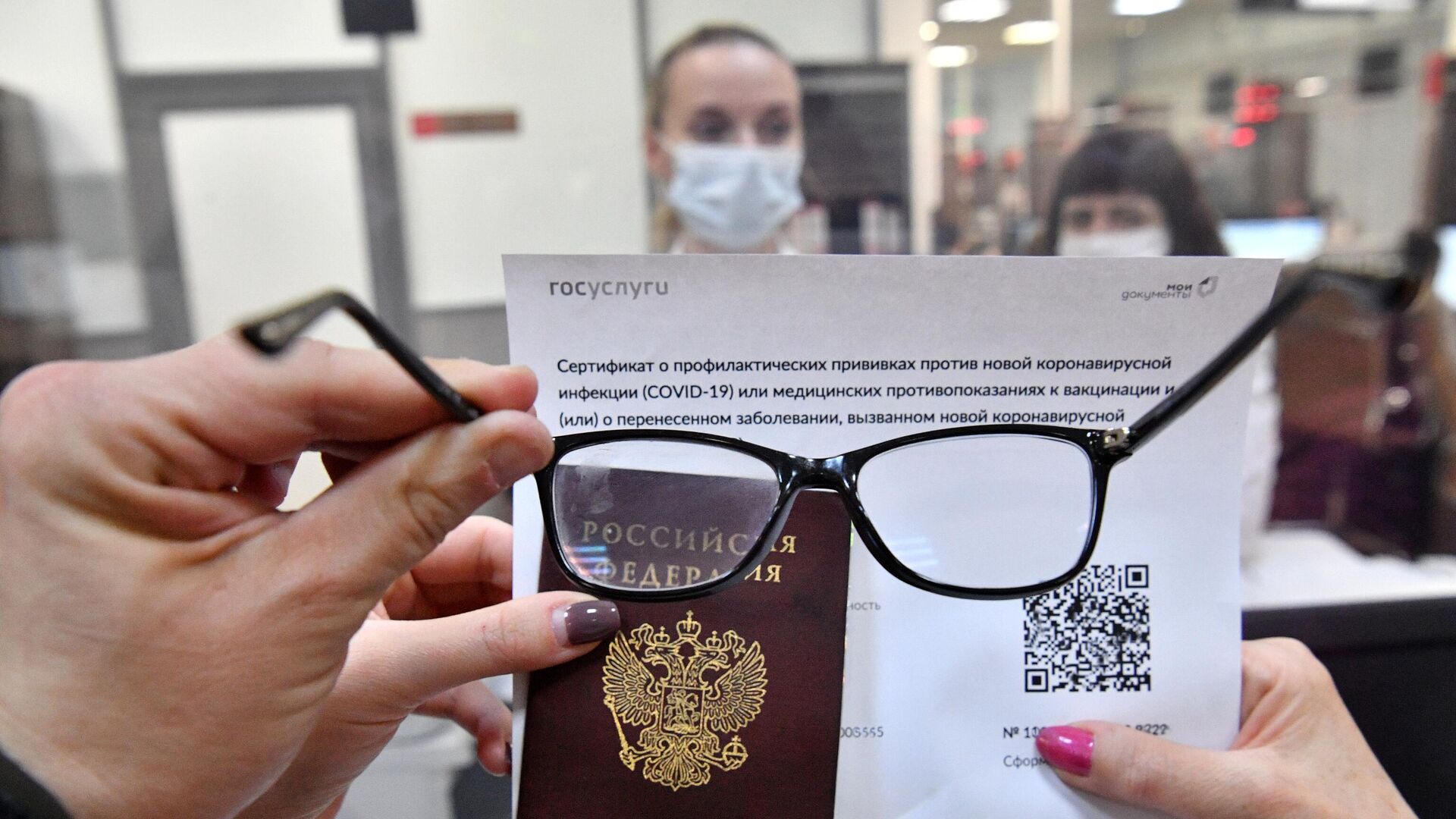 Посетитель осматривает распечатанный бумажный QR-код, полученный в многофункциональном центре госуслуг  - РИА Новости, 1920, 07.12.2021