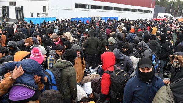 Беженцы с Ближнего Востока ожидают размещения возле центра временного содержания мигрантов, оборудованного в логистическом центре в пункте пропуска Брузги, на белорусско-польской границе