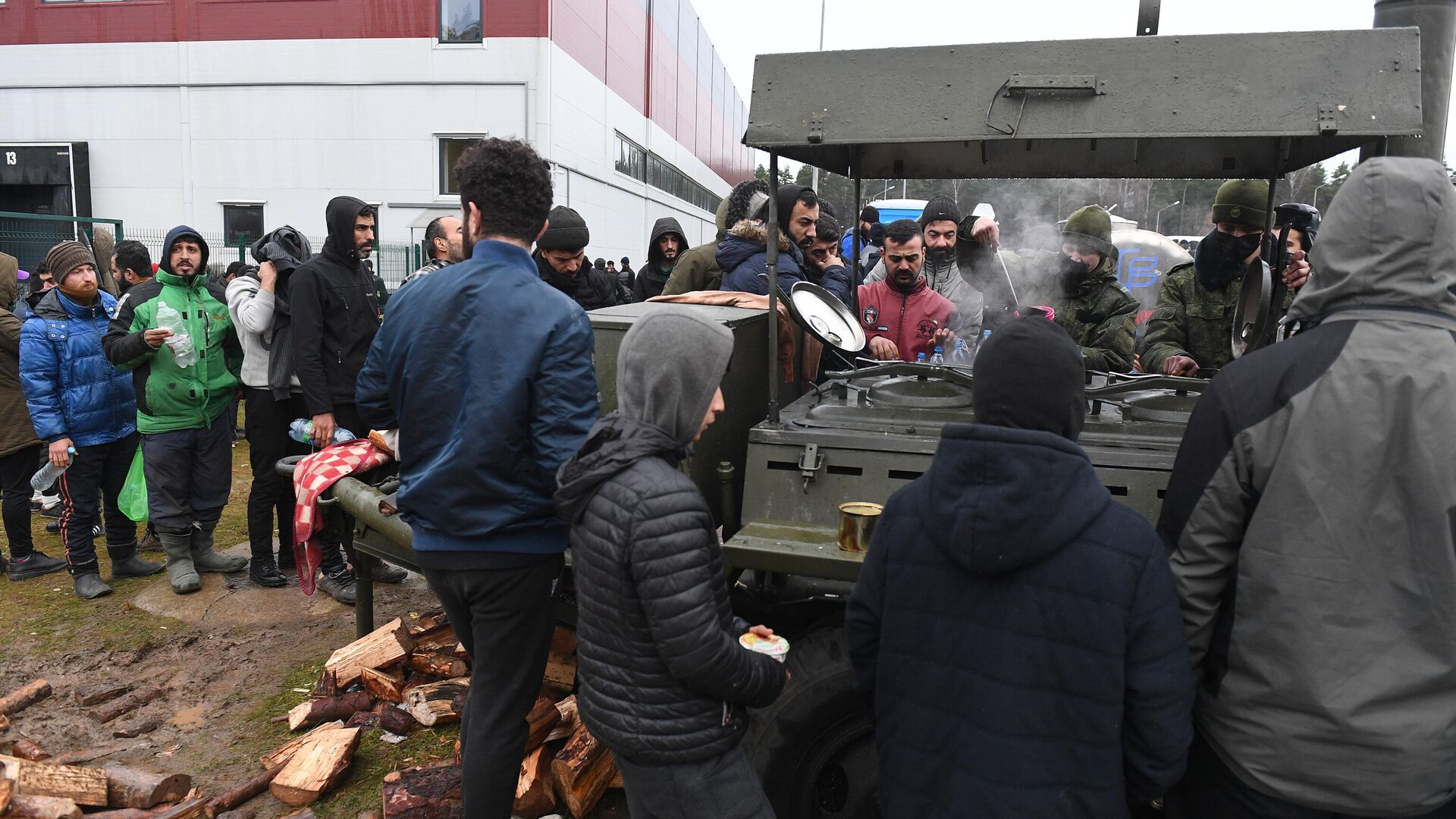 Беженцы с Ближнего Востока стоят в очереди возле полевой кухни на территории центра временного содержания мигрантов в логистическом центре в пункте пропуска Брузги - РИА Новости, 1920, 22.11.2021