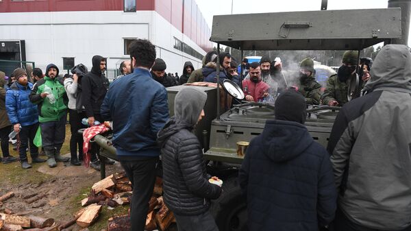 Беженцы с Ближнего Востока стоят в очереди возле полевой кухни на территории центра временного содержания мигрантов в логистическом центре в пункте пропуска Брузги