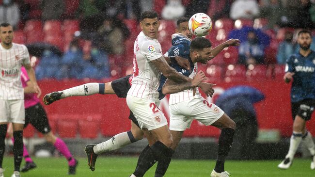 Sevilla's Brazilian defender Diego Carlos (L) fights for the ball with Alaves' Spanish midfielder Edgar Mendez during the Spanish league football match between Sevilla FC and Deportivo Alaves at the Ramon Sanchez Pizjuan stadium in Seville on November 20, 2021. (Photo by JORGE GUERRERO / AFP)