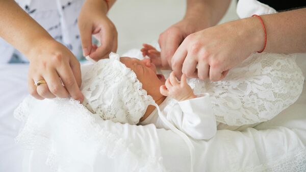 Родители пеленают новорожденного 