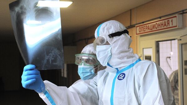 Врачи реаниматологи изучают рентгеновский снимок легких пациента в красной зоне больницы города Рассказово