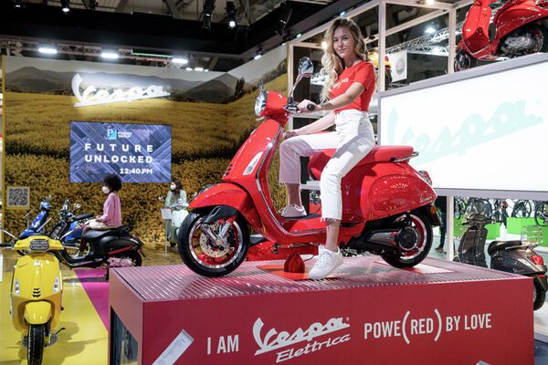 Модель позирует на электроскутере Vespa от Piaggio на в 78-й Международной выставке велосипедов и мотоциклов в Милане