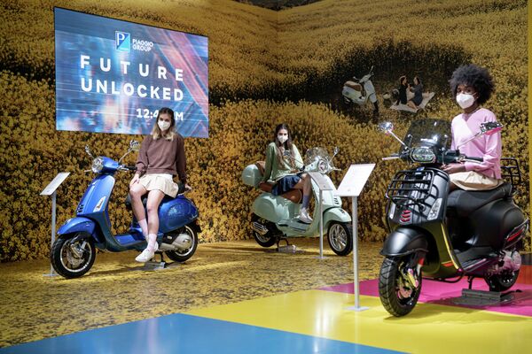 Модели представляют скутеры Vespa на 78-й Международной выставке велосипедов и мотоциклов в Милане Модели представляют скутеры Vespa на 78-й Международной выставке велосипедов и мотоциклов в Милане