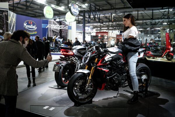 Мужчина фотографирует модель, представляющую мотоцикл MV Agusta на 78-й Международной выставке велосипедов и мотоциклов в Милане