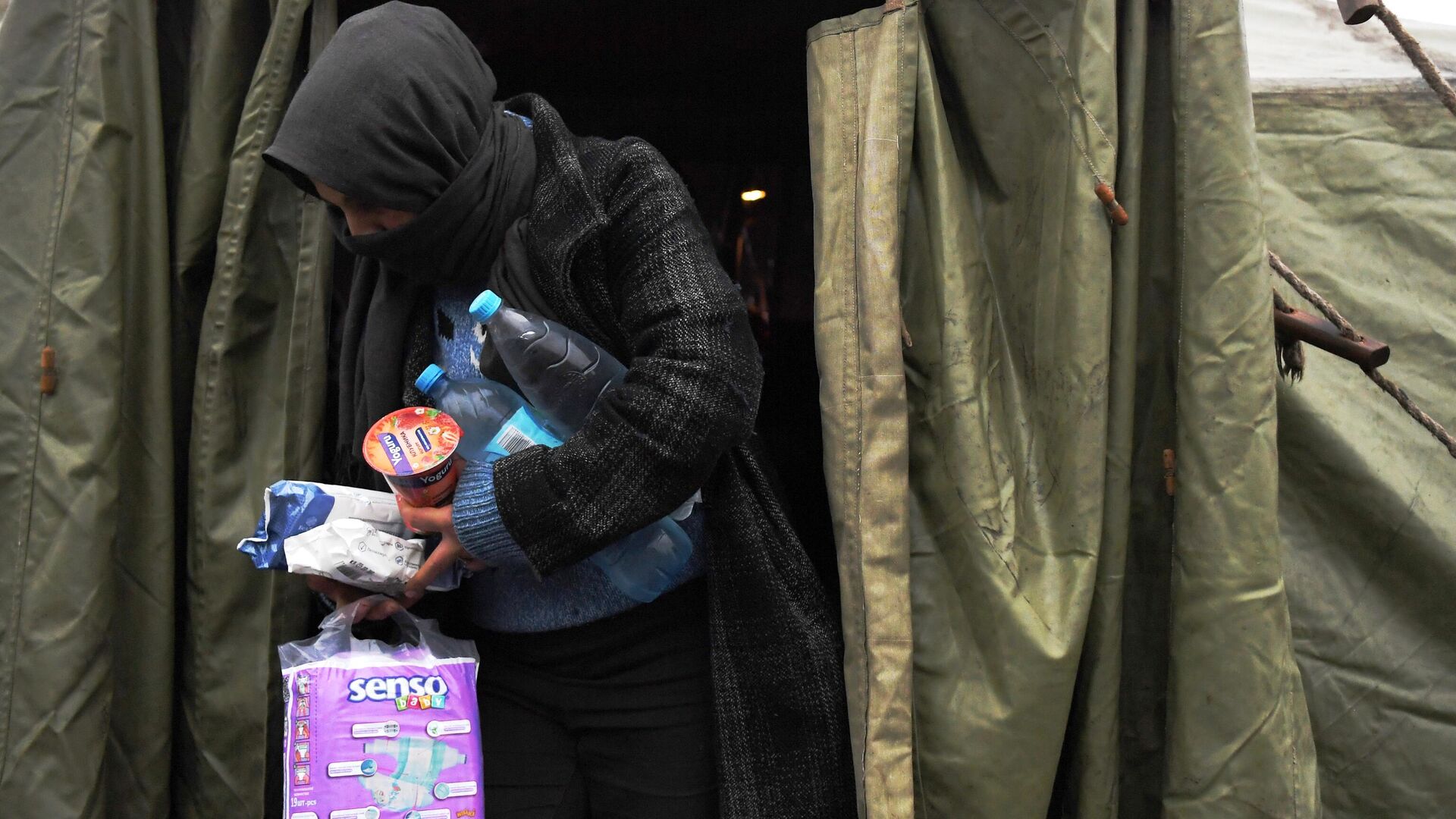 Женщина выходит из  палатки в центре временного содержания мигрантов, оборудованном в логистическом центре в пункте пропуска Брузги - РИА Новости, 1920, 24.11.2021