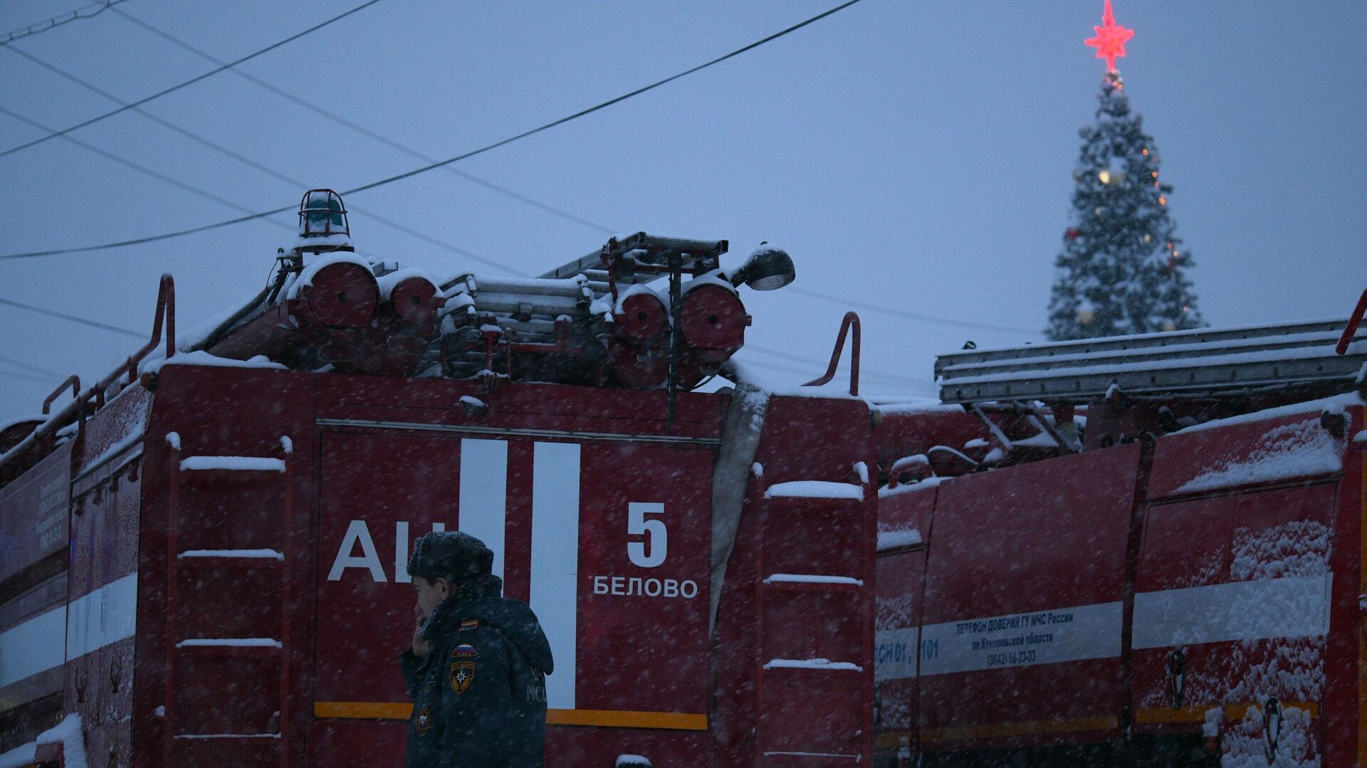Сотрудник полиции стоит возле машины противопожарной службы на территории шахты Листвяжная в городе Белово - РИА Новости, 1920, 25.11.2021
