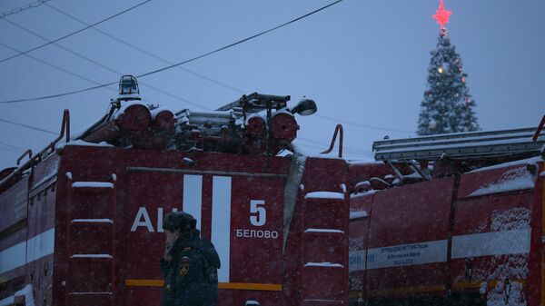 Сотрудник полиции стоит возле машины противопожарной службы на территории шахты Листвяжная в городе Белово