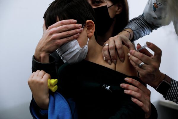 6-летний израильский ребенок на руках у своей матери получает вакцину Pfizer-BioNTech COVID-19 в Тель-Авиве, Израиль