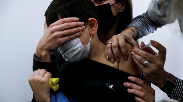 Ребенок на руках у своей матери получает вакцину Pfizer-BioNTech COVID-19 в Тель-Авиве, Израиль