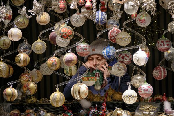 Продавец разговаривает по телефону на рождественской ярмарке в Вене, Австрия