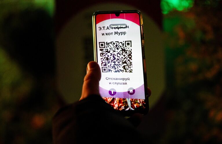 Посетитель с помощью QR-кода слушает аудиоматериалы шоу Сказки старой Европы в парке Юность в Калининграде