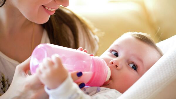 Мать кормит ребёнка из бутылочки для вскармливания