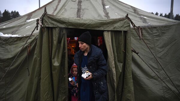Женщина выходит из продовольственной палатки в центре временного содержания мигрантов, оборудованном в логистическом центре в пункте пропуска Брузги