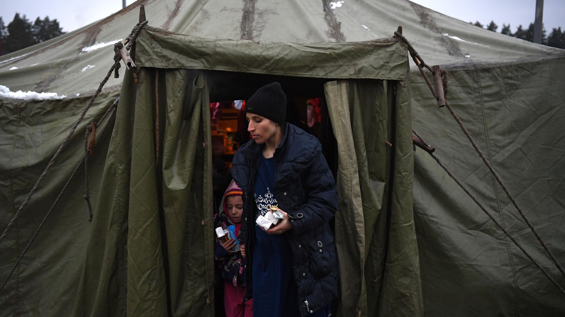 Женщина выходит из продовольственной палатки в центре временного содержания мигрантов, оборудованном в логистическом центре в пункте пропуска Брузги - РИА Новости, 1920, 28.11.2021