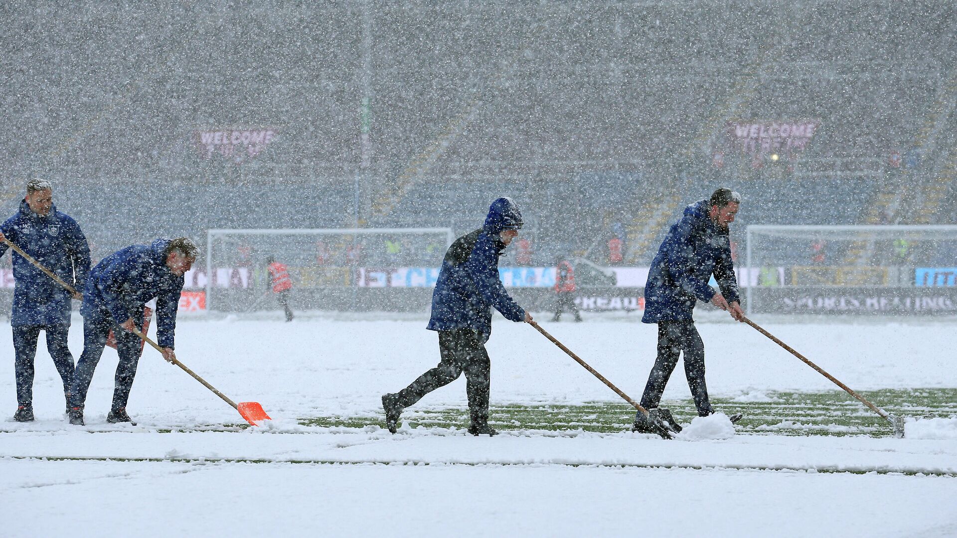 Ground staff clear snow from the pitch as the snow falls ahead of the English Premier League football match between Burnley and Tottenham Hotspur at Turf Moor in Burnley, north west England on November 28, 2021. - The game has since been postponed due to the weather. (Photo by Lindsey Parnaby / AFP) / RESTRICTED TO EDITORIAL USE. No use with unauthorized audio, video, data, fixture lists, club/league logos or 'live' services. Online in-match use limited to 120 images. An additional 40 images may be used in extra time. No video emulation. Social media in-match use limited to 120 images. An additional 40 images may be used in extra time. No use in betting publications, games or single club/league/player publications. /  - РИА Новости, 1920, 28.11.2021