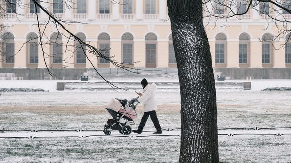 Девушка с коляской гуляет по территории Михайловского сада в Санкт-Петербурге
