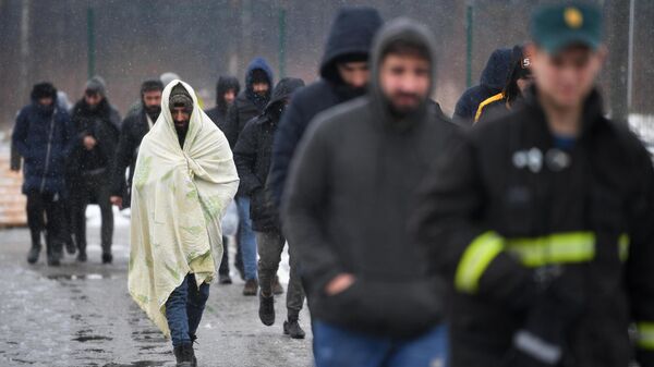 Беженцы с Ближнего Востока идут после купания в полевой бане в лагере мигрантов, оборудованном в логистическом центре в пункте пропуска Брузги на белорусско-польской границе