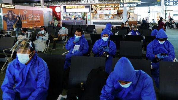 Пассажиры в защитных костюмах в аэропорту Сукарно-Хатта в Индонезии