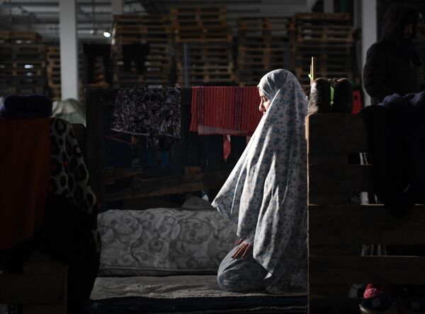Женщина молится в центре временного содержания мигрантов, оборудованном в логистическом центре в пункте пропуска Брузги, на белорусско-польской границе