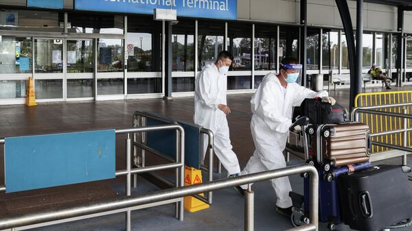Пассажиры в защитных костюмах в аэропорту Сиднея