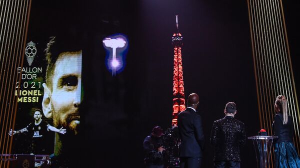 Ballon d'Or award recipient Paris Saint-Germain's Argentine forward Lionel Messi (2R), and evening hosts French-British journalist Sandy Heribert (R) and Ivorian former football player  Didier Drogba (3R) watch a broadcast of a display at the Trocadero Esplanade and the Eiffel Tower in honour of Messi's award during the 2021 Ballon d'Or France Football award ceremony at the Theatre du Chatelet in Paris on November 29, 2021. (Photo by FRANCK FIFE / AFP)