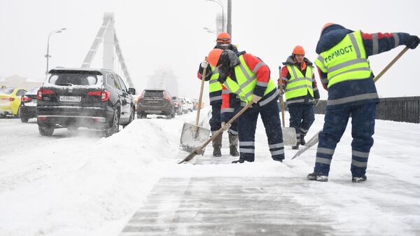 Сотрудники ГБУ Гормост очищают от снега и наледи Крымский мост во время снегопада в Москве